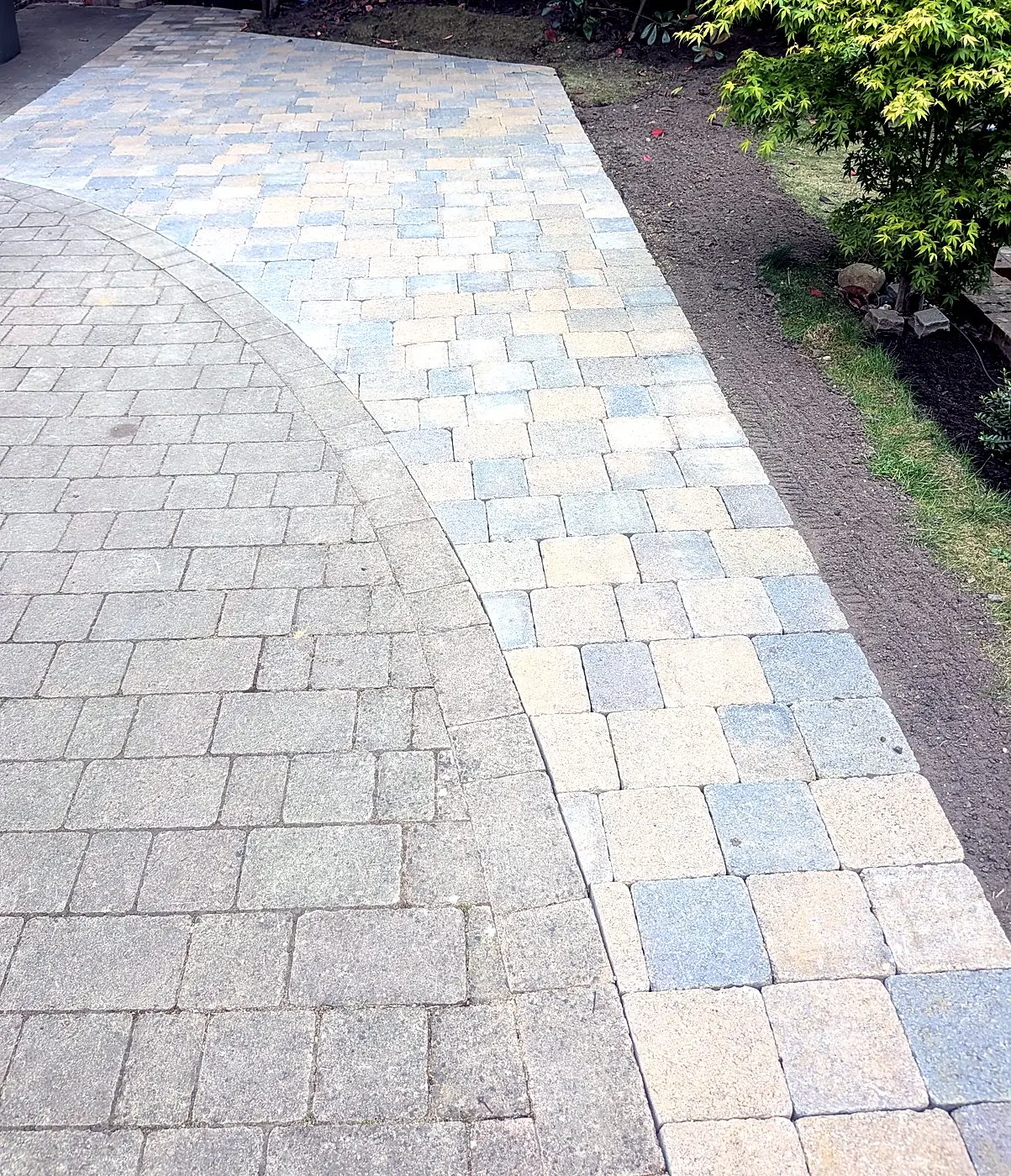 Curved multi-tone block paving installed beside a lawn