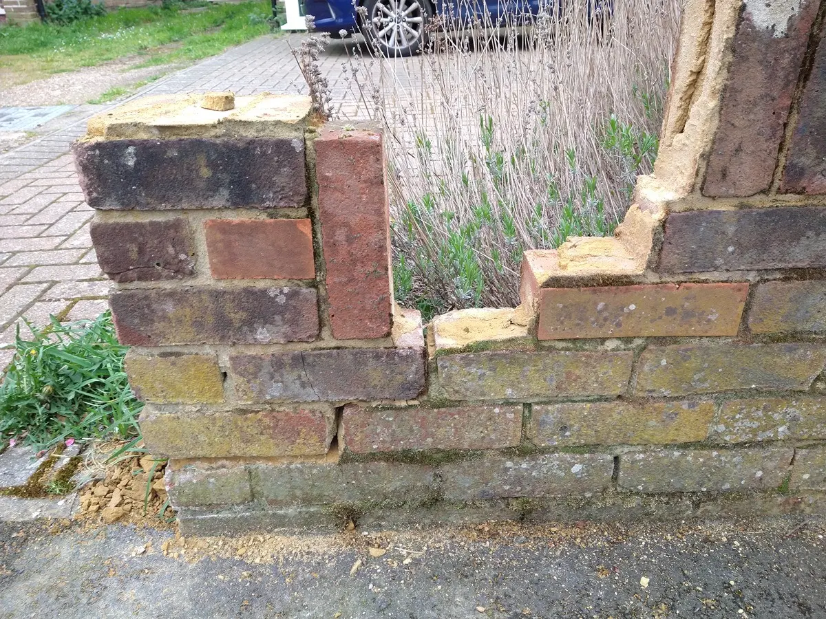 Damaged brick garden wall before repair