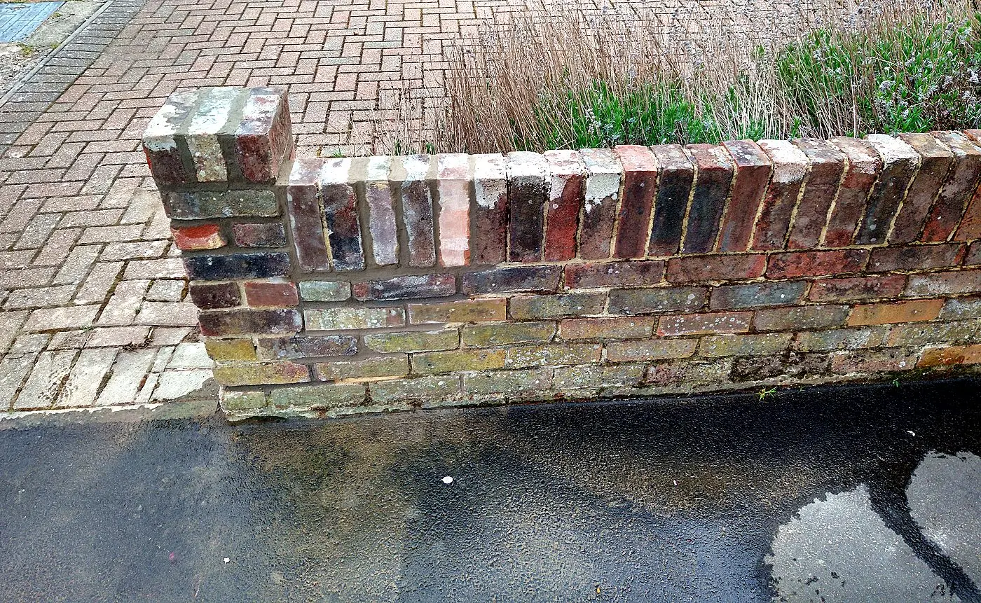 Rebuilt low brick garden wall with soldier-course top