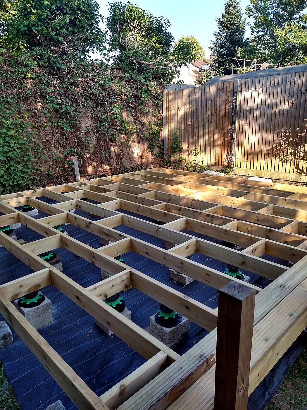 Levelled deck framing on pedestals with weed membrane