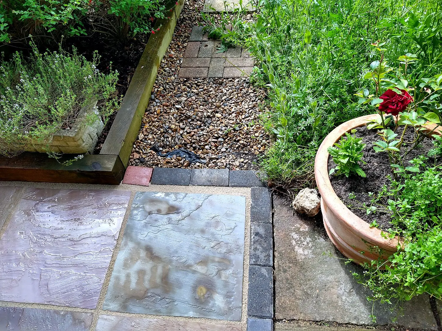Natural stone patio with brick edging, gravel path, and planting